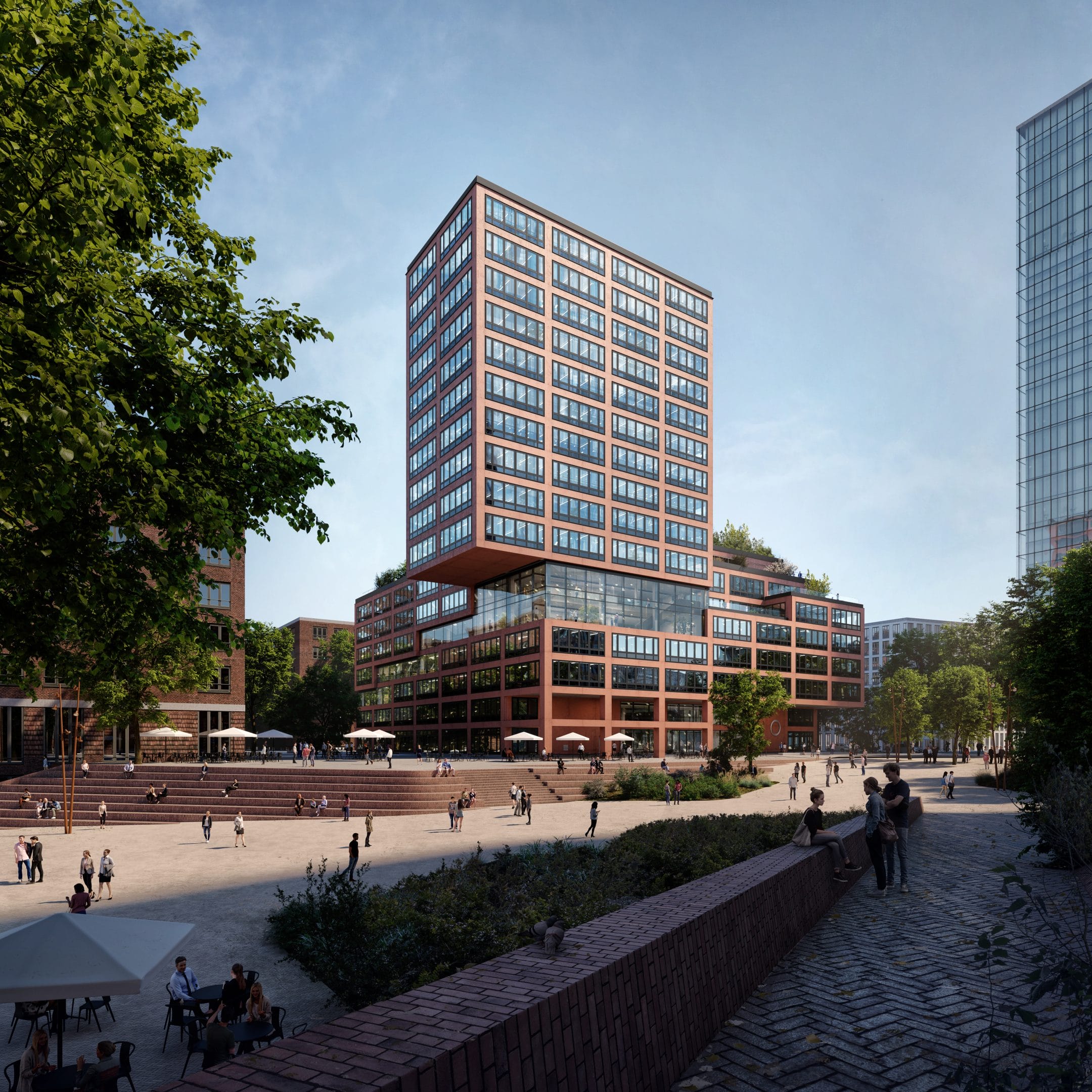 A modern, multi-story red and brown building on a city square teeming with pedestrians offers dedicated workspaces. The area has lush trees, flowering plants, and tiered stone seating leading to the waterfront An image from EDGE Workspaces.