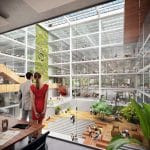 Ein modernes mehrstöckiges Atrium mit einem großen grünen vertikalen Garten. Menschen laufen herum und sitzen auf Bänken. Die Architektur zeichnet sich durch Holzelemente, Glaswände und Treppen aus und schafft eine helle und luftige Atmosphäre. An image from EDGE Workspaces.